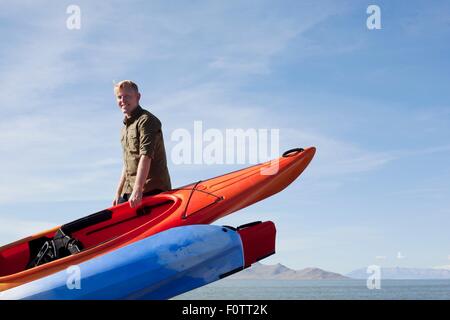 Junge Mann trägt orange Kajak, Blick auf die Kamera zu Lächeln Stockfoto