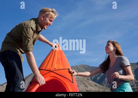 Junges Paar orange Kajak, sahen einander lächelnd vorbereiten Stockfoto