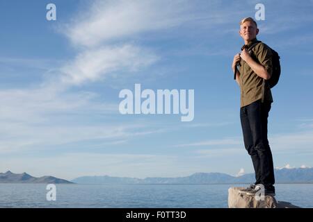 Junger Mann mit Rucksack stehen auf Felsen wegsehen, Great Salt Lake City, Utah, USA Stockfoto