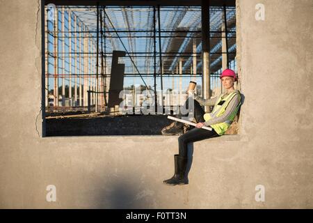 Architektin sitzen auf Fensterrahmen auf Baustelle Stockfoto