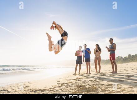 Gruppe von Freunden am Strand beobachten Freund Sprung in der Luft Stockfoto