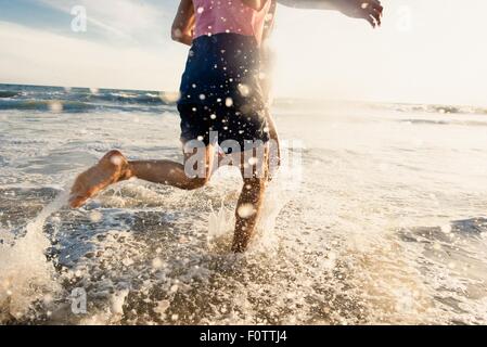 Junger Mann läuft im Meer, niedrige Abschnitt Stockfoto