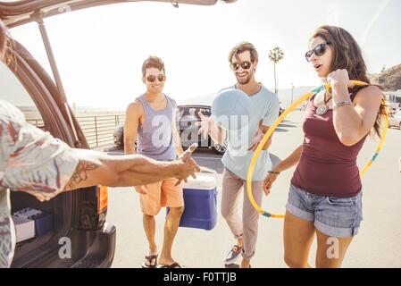 Gruppe von Freunden mit dem Auto stehen, Picknick und spielen Elemente halten Stockfoto