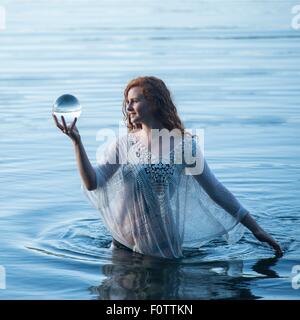 Junge Frau im See Blick auf Crystal ball Stockfoto