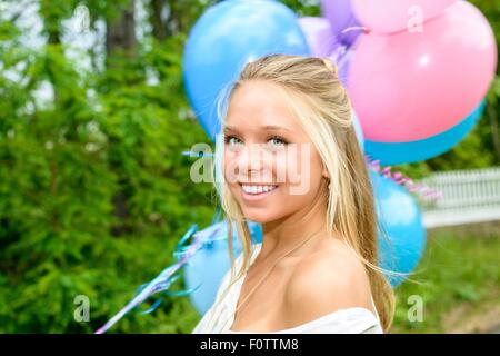 Porträt der hübsche junge Frau mit langen blonden Haaren halten Haufen Luftballons Stockfoto