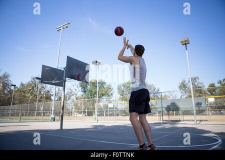 Junge männliche Basketball-Spieler wirft Ball in Richtung Basketballkorb Stockfoto