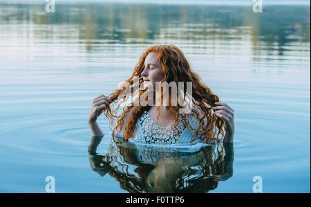 Kopf und Schultern der schöne junge Frau mit langen roten Haaren in See Stockfoto