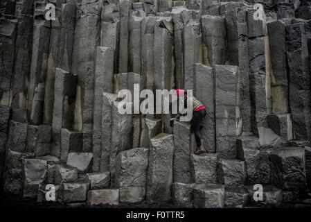 Weibliche Touristen Klettern auf Felsformation, Reynisfjara, Island Stockfoto