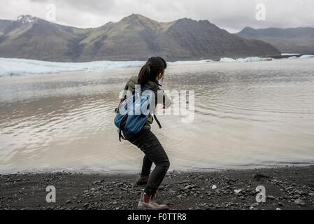 Rückansicht des weiblichen Touristen skimming Steinen im Meer, Skaftafell, Island Stockfoto