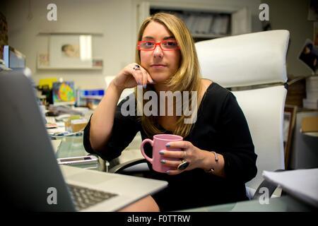 Porträt der jungen Frau im Büro, am Schreibtisch, mit Kaffeetasse Stockfoto