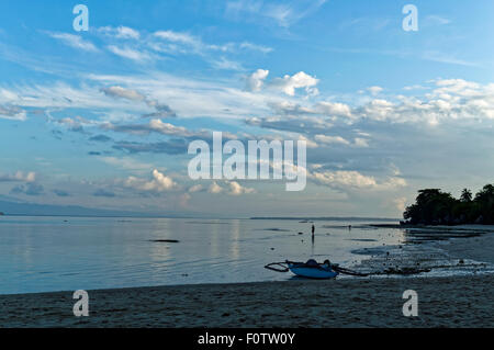 Ein blauer Morgen am Strand. Es gibt ein paar Leute um, Boote sind links am Ufer und das Wasser ist zurückgegangen nach außen. Stockfoto