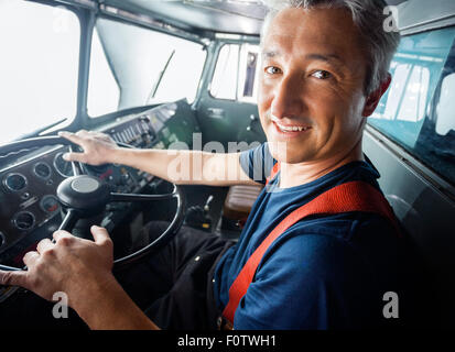 Glücklich Feuerwehrmann fahren Feuerwehrauto Stockfoto