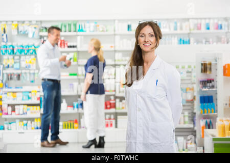 Chemiker, lächelnd, während der Assistent und Kundenservice stehen im Hinterg Stockfoto