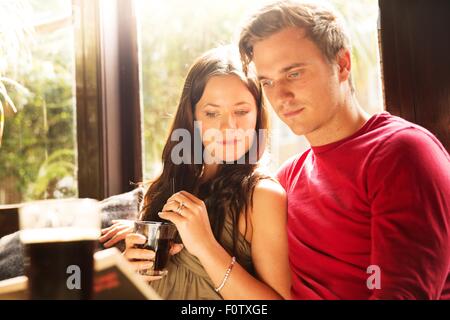 Paar-Sitzung mit einem Drink zusammen lesen Zeitung Stockfoto