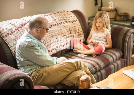 Großvater und Enkelin Spielkarten auf sofa Stockfoto