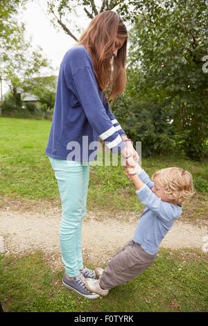 Teenager-Mädchen mit Kleinkind Bruder stehen auf ihren Füßen im Garten Stockfoto