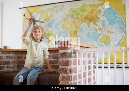 Junge sitzt vor Weltkarte spielen mit Spielzeug Flugzeug Stockfoto