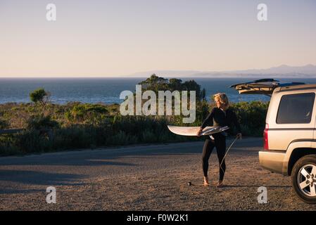 Junge männliche Surfer Surfbrett aus LKW an Küste entfernen Stockfoto