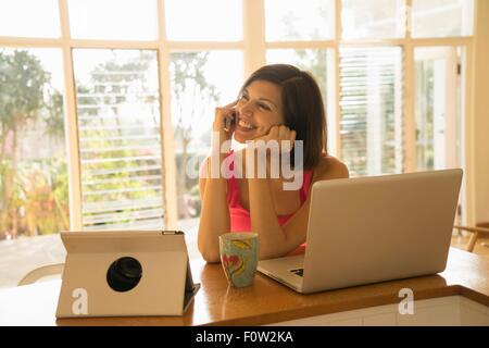 Geschäftsfrau im Chat auf Smartphone, Laptop im Wohnzimmer bei Verwendung Stockfoto