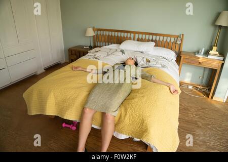 Mitte Erwachsene Frau auf Bett liegend mit offenen Armen Stockfoto