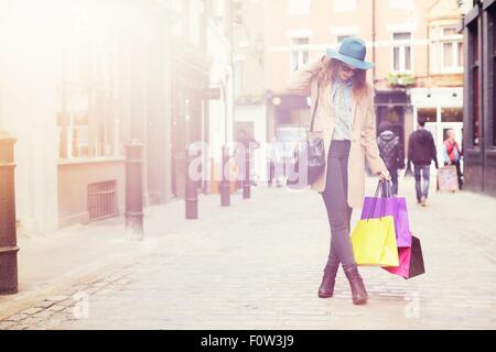 Porträt der stilvolle junge Frau mit Einkaufstüten, London, UK Stockfoto