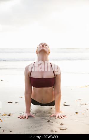 Mitte Erwachsene Frau üben Plank-Yoga-Pose am Strand Stockfoto