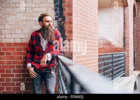 Mann mit Bart, stützte sich auf Balkon wegschauen Stockfoto