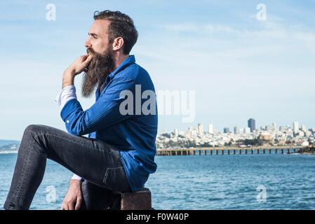 Mann mit Bart sitzt am Hafen Point, San Francisco, Kalifornien, USA Stockfoto