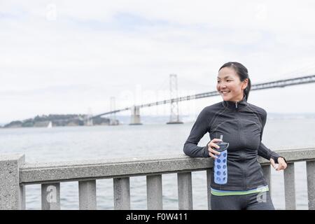 Weibliche Läufer Pause, Bay Bridge im Hintergrund, San Francisco, Kalifornien Stockfoto