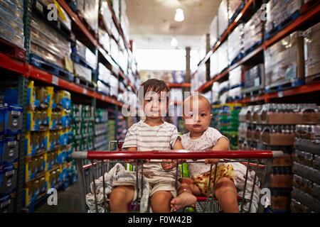 Brüder im Einkaufswagen sitzen Stockfoto
