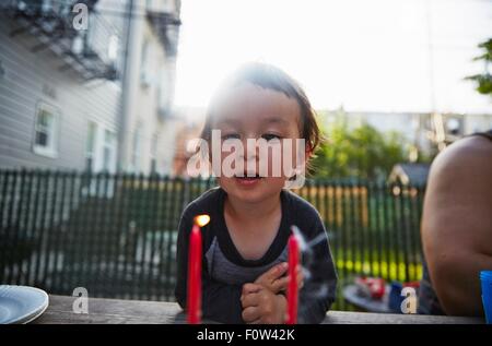 Junge Blick auf brennende Kerze auf Esstisch Stockfoto