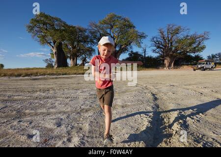 Junge spielt auf Schotterweg, Nxai Pan Nationalpark, Kalahari-Wüste, Afrika Stockfoto