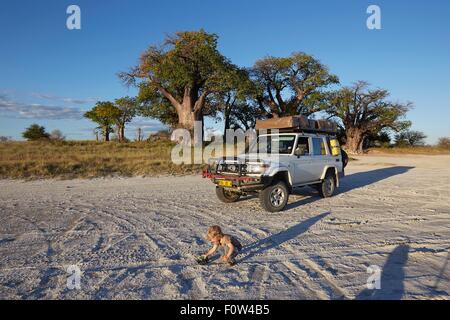 Jungen spielen von Fahrzeug, Nxai Pan Nationalpark, Kalahari-Wüste, Afrika Stockfoto