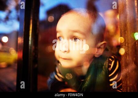 Junge Blick durch Fenster Stockfoto