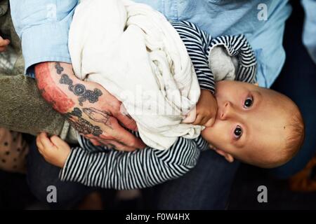 Baby Junge liegend auf Vaters Oberschenkel Stockfoto