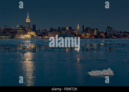 Gefrorene Midtown Manhattan NYC-Midtown Manhattan, New York City Skyline mit dem Empire State Building zusammen mit anderen Wolkenkratzer und seitlichem Blick auf das Chrysler Building ist abends beleuchtet. Die Hudson River ist ziemlich viel auf eine klare, aber sehr kühlen Winterabend eingefroren. Der Skyline leuchtet Gebäude Leuchten an der offenen kalten Gewässern während der Blauen Stunde nach Sonnenuntergang wider. Stockfoto