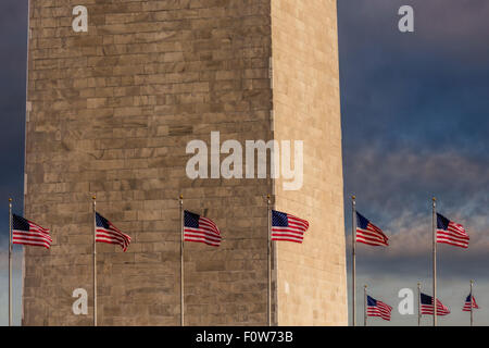 Schließen Sie die Ansicht des unteren Teils des Washington Monuments mit den Vereinigten Staaten von Amerika Flaggen, die rund um das Denkmal. Stockfoto