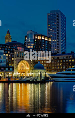 Boston Harbor und den Financial District in der Dämmerstunde. Das Custom House Clock Tower beleuchtet sowie Rowes Wharf, die Odyssey Cruise Yacht, zusammen mit anderen Hochhäuser entlang der Uferpromenade zu sehen. Stockfoto