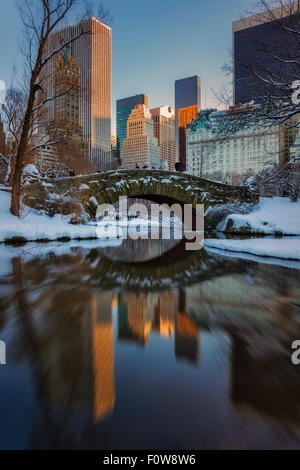 Gapstow Brücke spiegelt sich in den Teich während des Sonnenuntergangs am Central Park in New York City nach einem Schneesturm. Stockfoto