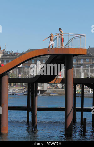 Boy Jumping from Kalvebod Bølge, Kalvebod Wellen im inneren Hafen von Kopenhagen bei Kalvebod Brygge. Urbaner Raum, sozialer Hub, Veranstaltungsort für Wassersport Stockfoto