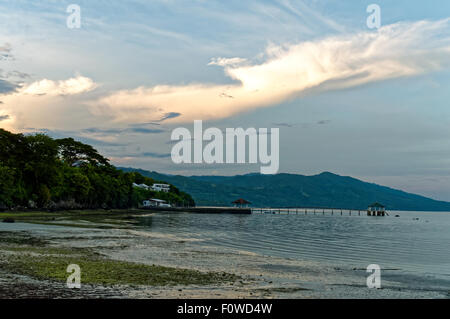 Ein blauer Morgen am Strand. Es gibt ein paar Leute um, Boote sind links am Ufer und das Wasser ist zurückgegangen nach außen. Stockfoto