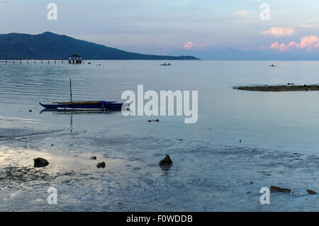 Ein blauer Morgen am Strand. Es gibt ein paar Leute um, Boote sind links am Ufer und das Wasser ist zurückgegangen, nach außen Stockfoto