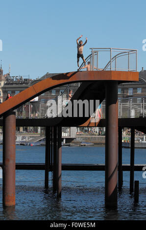 Boy Springen aus dem Kalvebod Bølge, Kalvebod Wellen oder Welle, im inneren Hafen von Kopenhagen. Urbaner Raum, sozialer Hub, Veranstaltungsort für Wassersport. Stockfoto