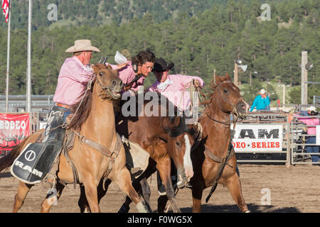 Estes Park, Colorado - Bareback riding Wettbewerb beim Rodeo auf dem Dach. Pickup Fahrer helfen ein Konkurrent (Mitte) von seinem Pferd Stockfoto