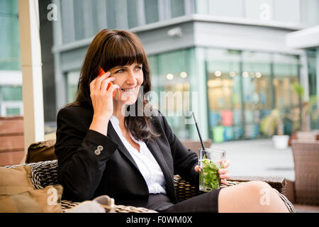 Senior Business-Frau outdoor im street Bar und Anrufende Telefonnummer Mojito trinken Stockfoto