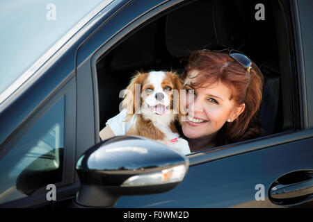 Porträt von Reife Frau mit ihrem cavalier Hund durch Seitenfenster des Autos Stockfoto