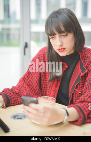 Junge schöne kaukasischen Frau sitzend auf eine Bar mit einem Smartphone - Kommunikation, Technologie, soziale Netzwerk-Konzept Stockfoto