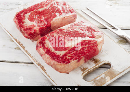 Rohes Frischfleisch Ribeye Steak auf einem weißen Hintergrund aus Holz. Stockfoto