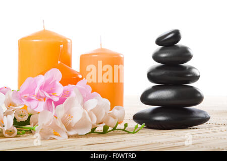 Stillleben mit schwarzem Stein und orange Kerze, auf weißem Hintergrund, isoliert Stockfoto