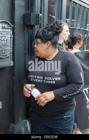 Cable Street, London, 22. August 2015. Aktivisten aus Klassenkampf demonstrieren gegen die neu gegründete Jack The Ripper Museum auf Kabel-Straße, behauptet, dass es Frauen erniedrigt, profitieren Sie von dem Tod der Prostituierten von den Ripper getötet. Das Museum behauptete während der Planungsphase, der Suffragetten-Bewegung gewidmet sein würde. Bild: Eine Frau, die offenbar arbeitet als Wachmann für das Museum trägt eine Sweatshirt "Kampf gegen alles löst" zu verkünden. Bildnachweis: Paul Davey/Alamy Live-Nachrichten Stockfoto